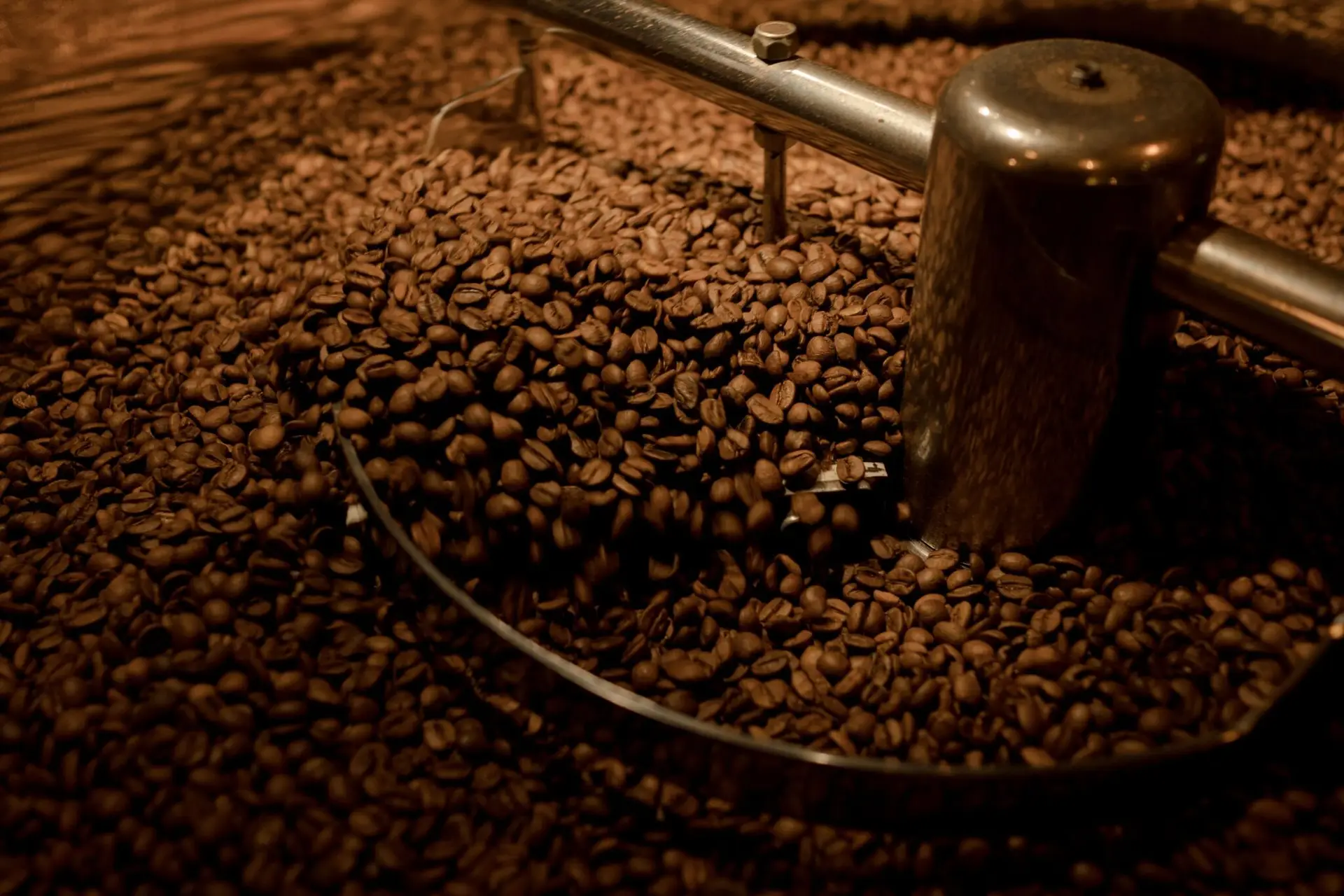 Detailed view of coffee beans being roasted in an industrial roaster. Perfect for coffee enthusiasts.